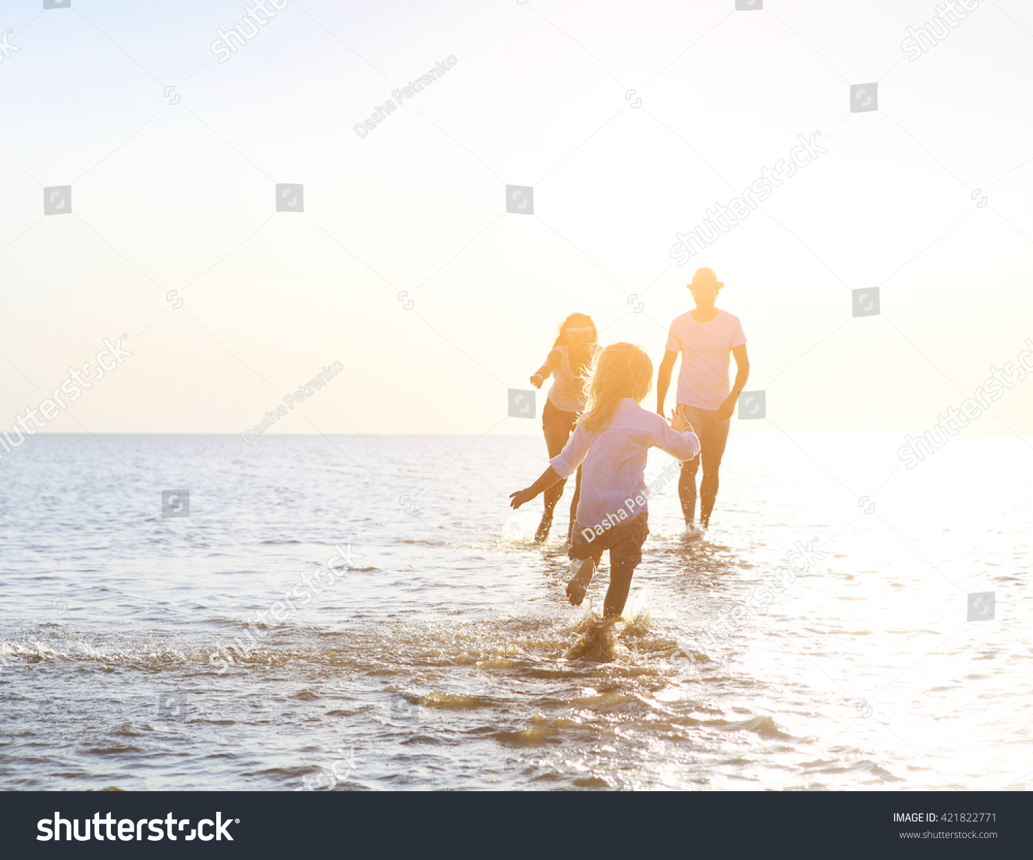 Happy young family having fun running on beach at sunset. Family traveling concept #421822771
