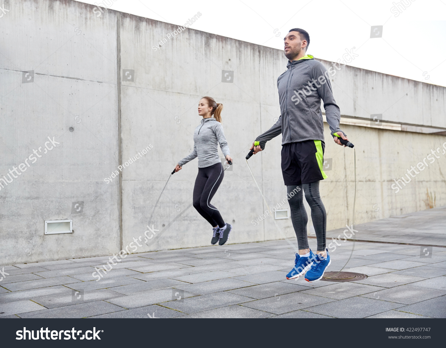 fitness, sport, people, exercising and lifestyle concept - man and woman skipping with jump rope outdoors #422497747