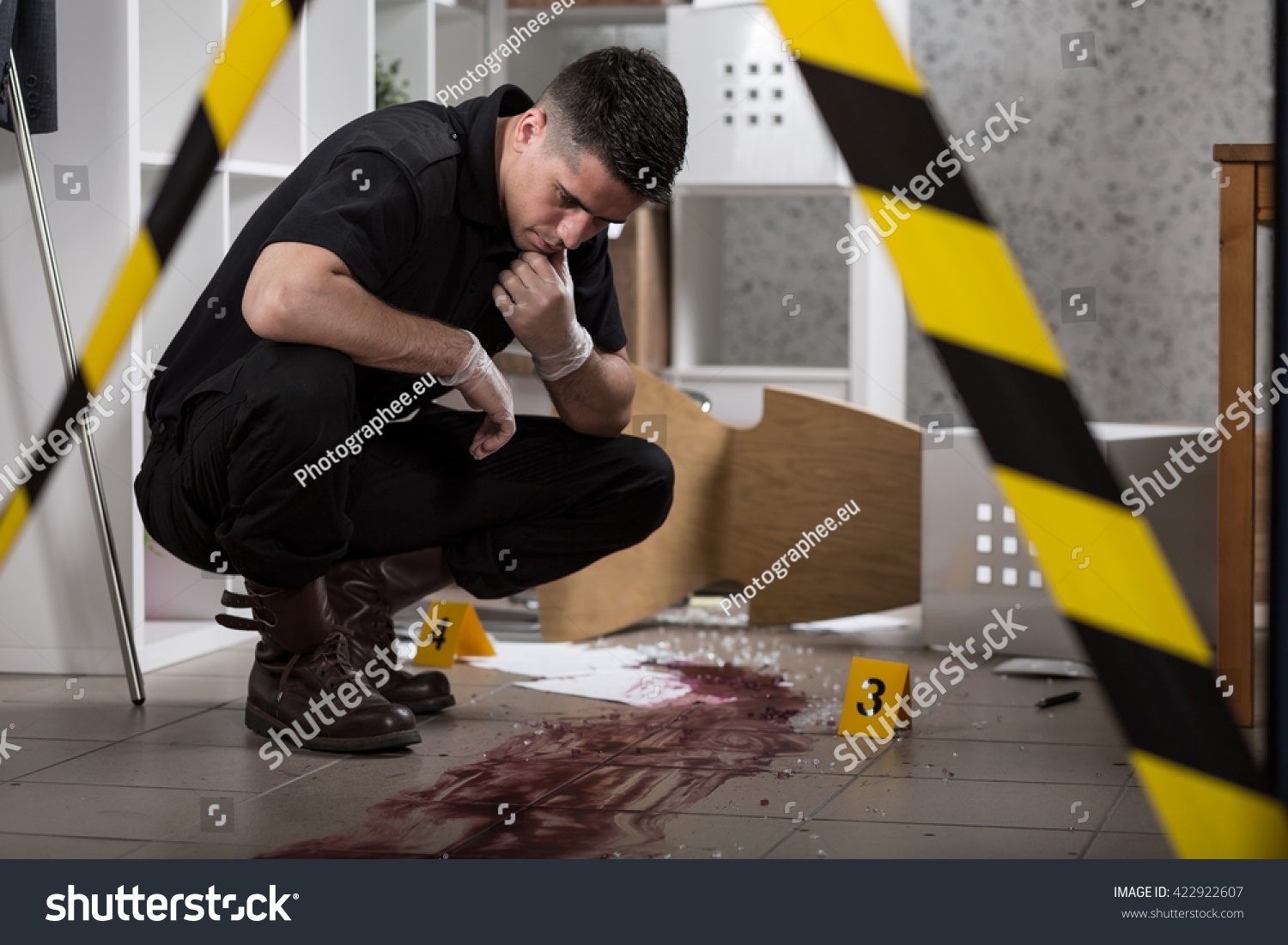Young policeman collecting evidence standing behhind yellow crime scene tape #422922607