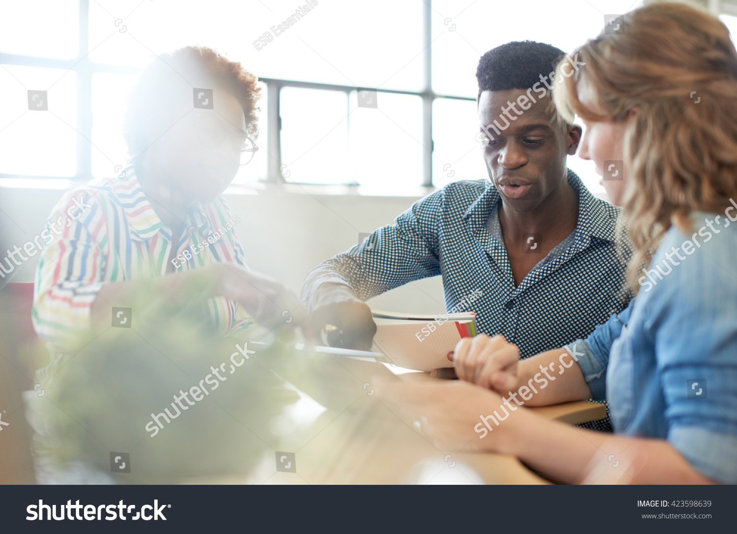 Unposed group of creative business people in an open concept office brainstorming their next project. #423598639