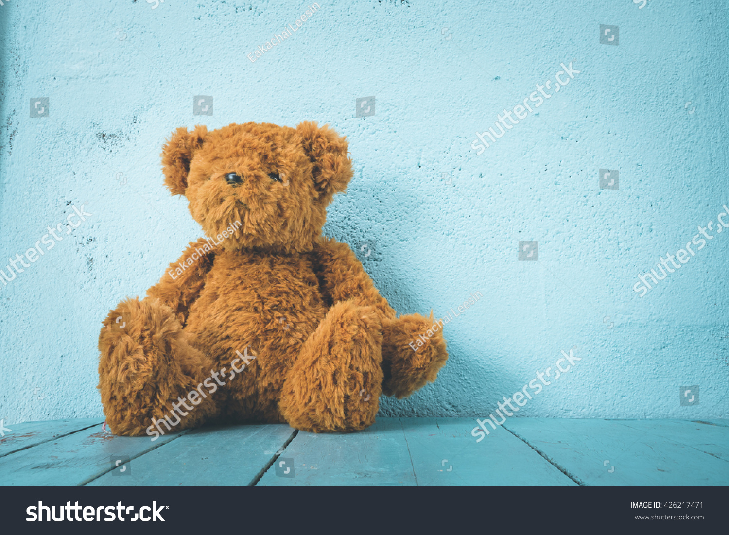 Teddy bear on a table have blue background, alone   #426217471