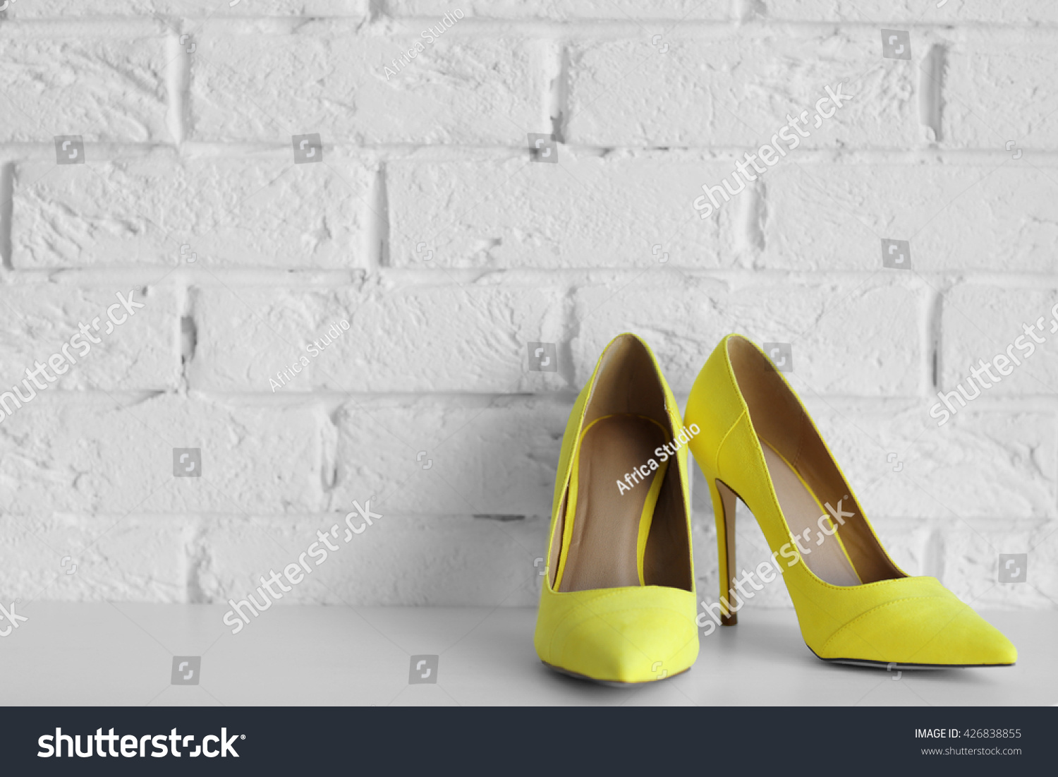 Yellow woman high heels on a brick wall background #426838855