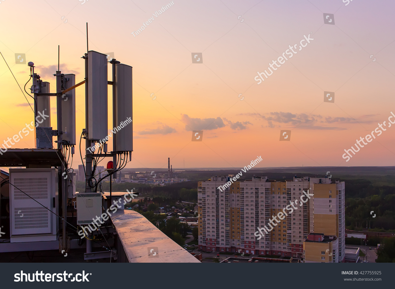 cellular communications tower on a background of the city and a beautiful sunset in summer #427755925