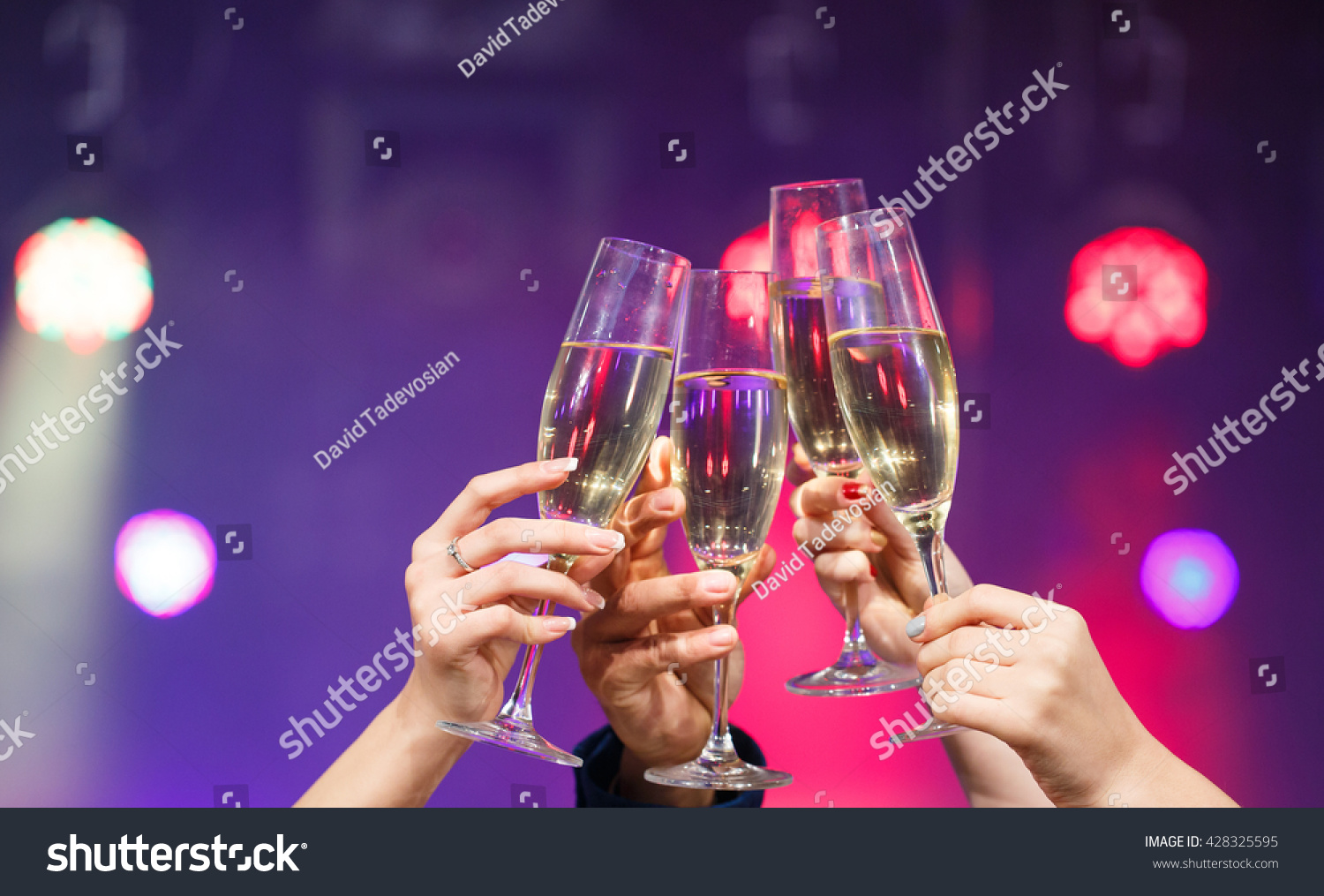 Clinking glasses of champagne in hands on bright lights background #428325595