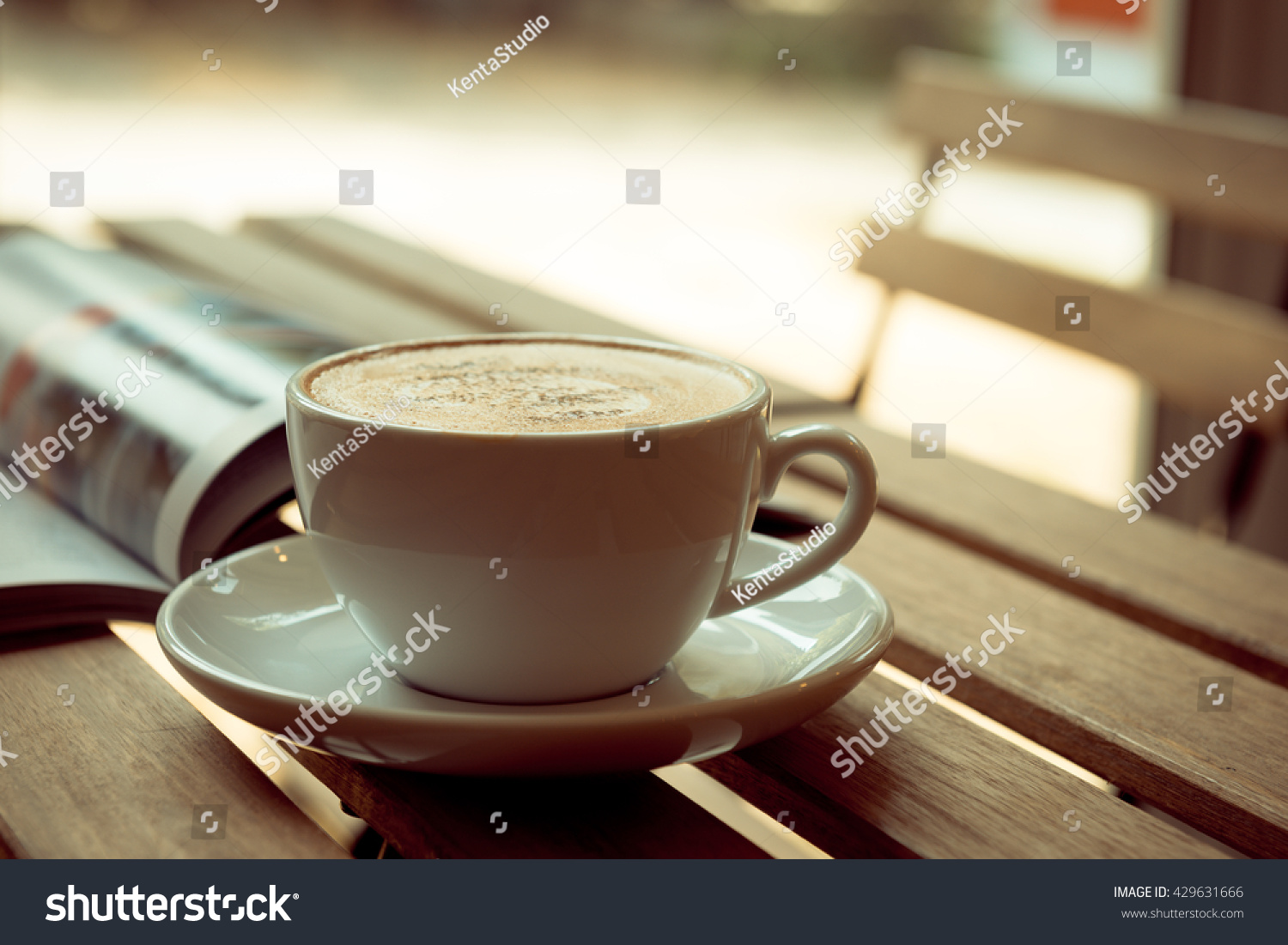 mug of hot coffee and opened book on table near windows #429631666
