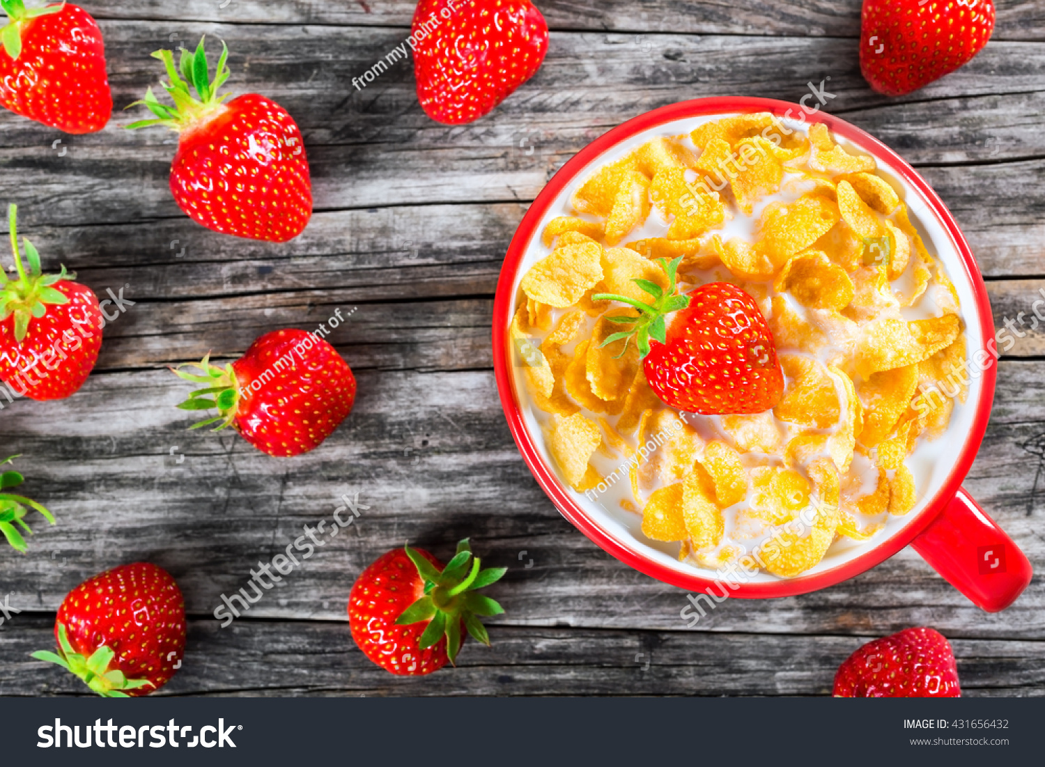 corn flakes with milk and strawberry in a red cup on an old rustic table, close-up, top view  #431656432