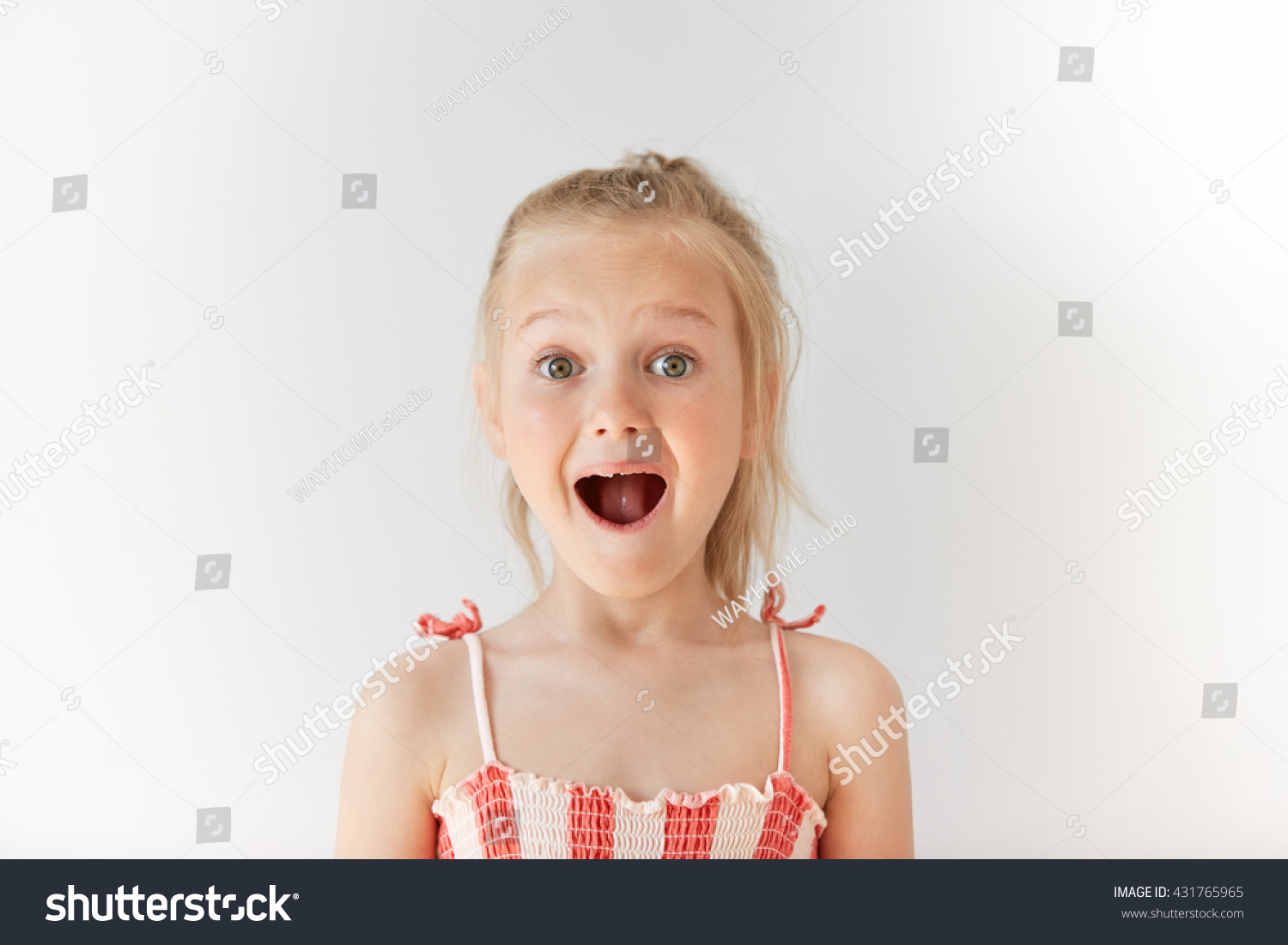 Little European girl opening mouth in surprise and raising her eyebrows with wonder. Blond child with naive glance, trustful simplicity and amazed face. #431765965