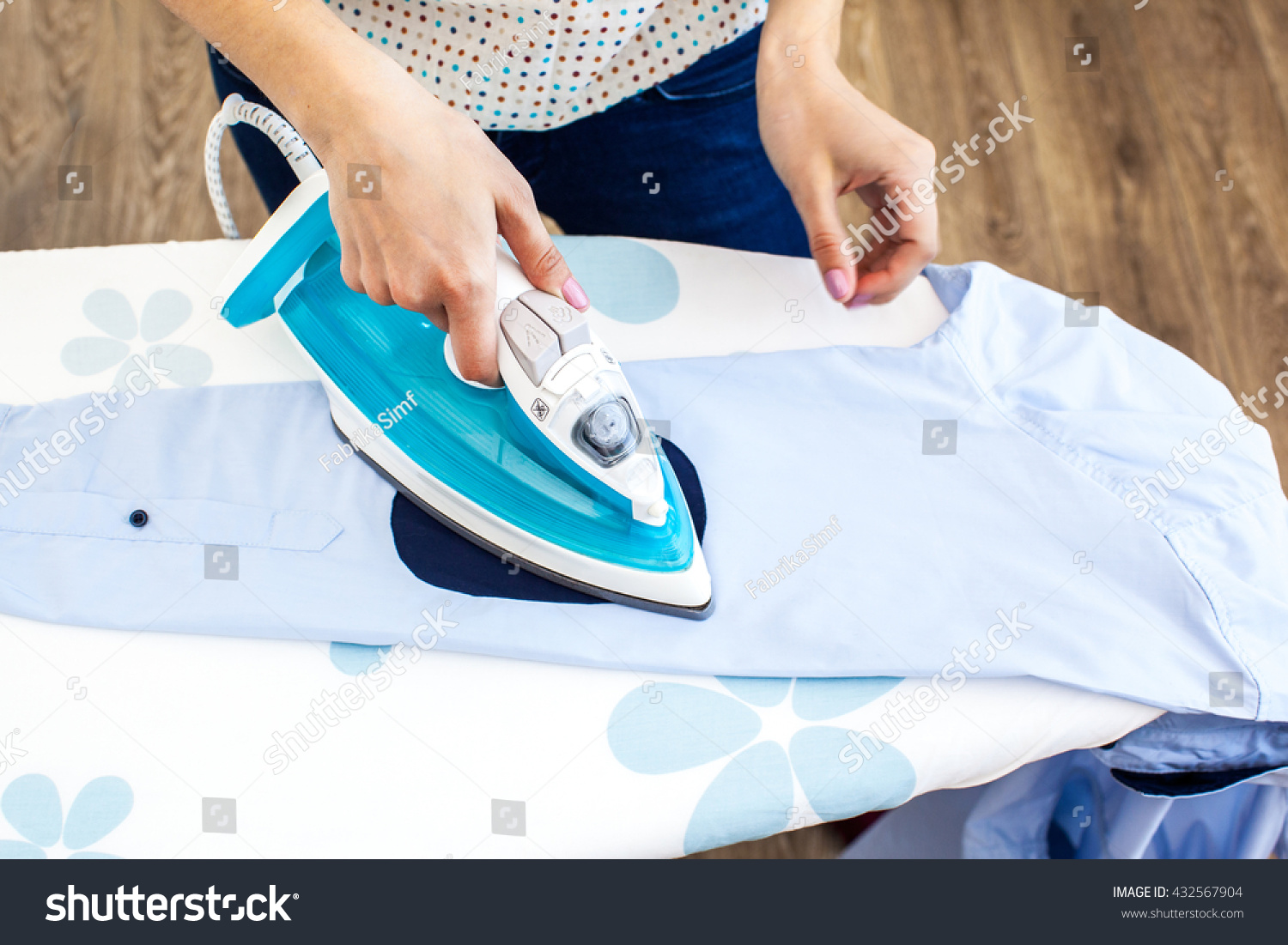 Closeup of woman ironing clothes on ironing board #432567904
