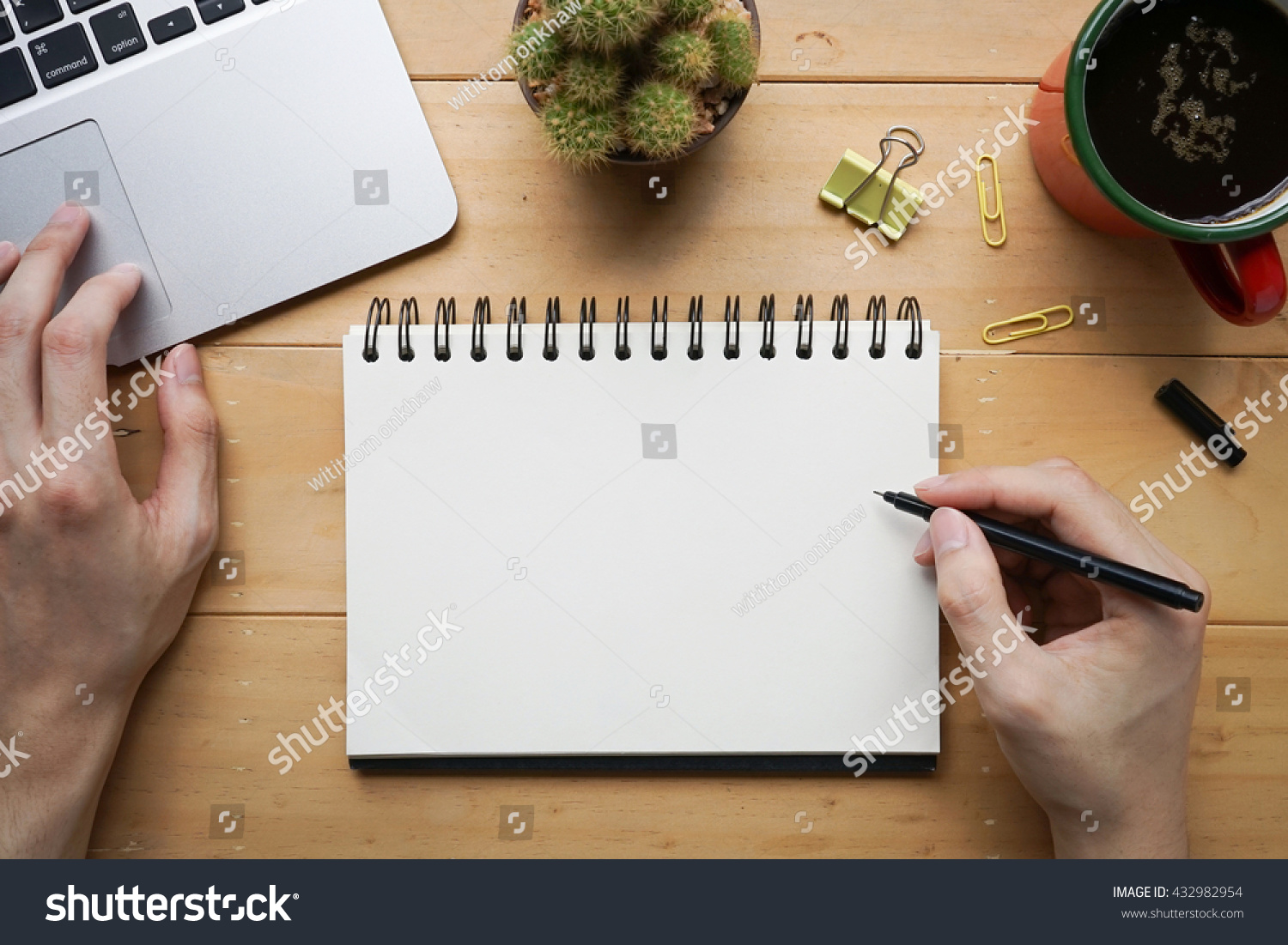 Person sketching or taking note down on blank open notebook with cup of fresh coffee on desk #432982954