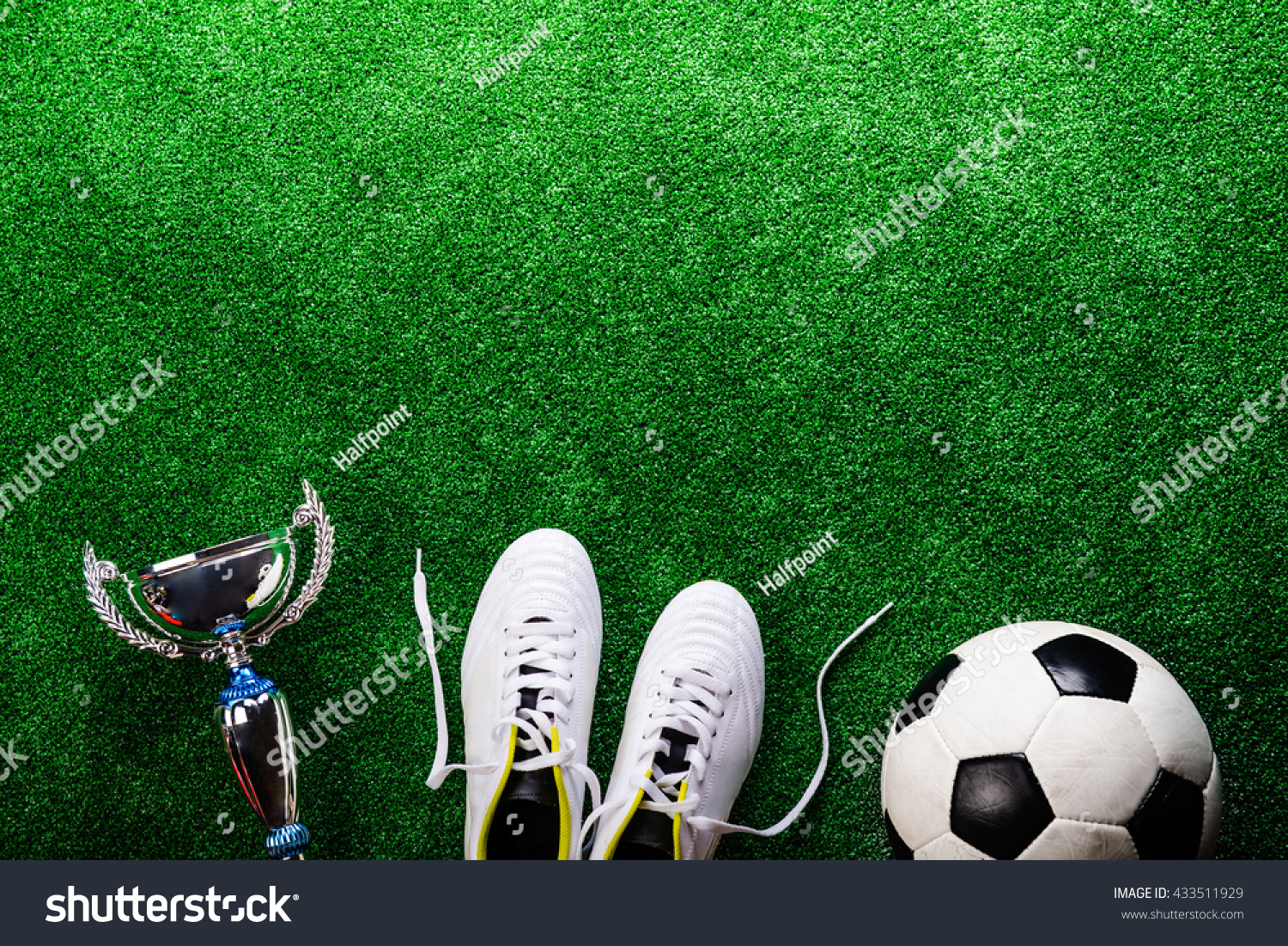 Soccer ball, cleats and trophy against green artificial turf #433511929