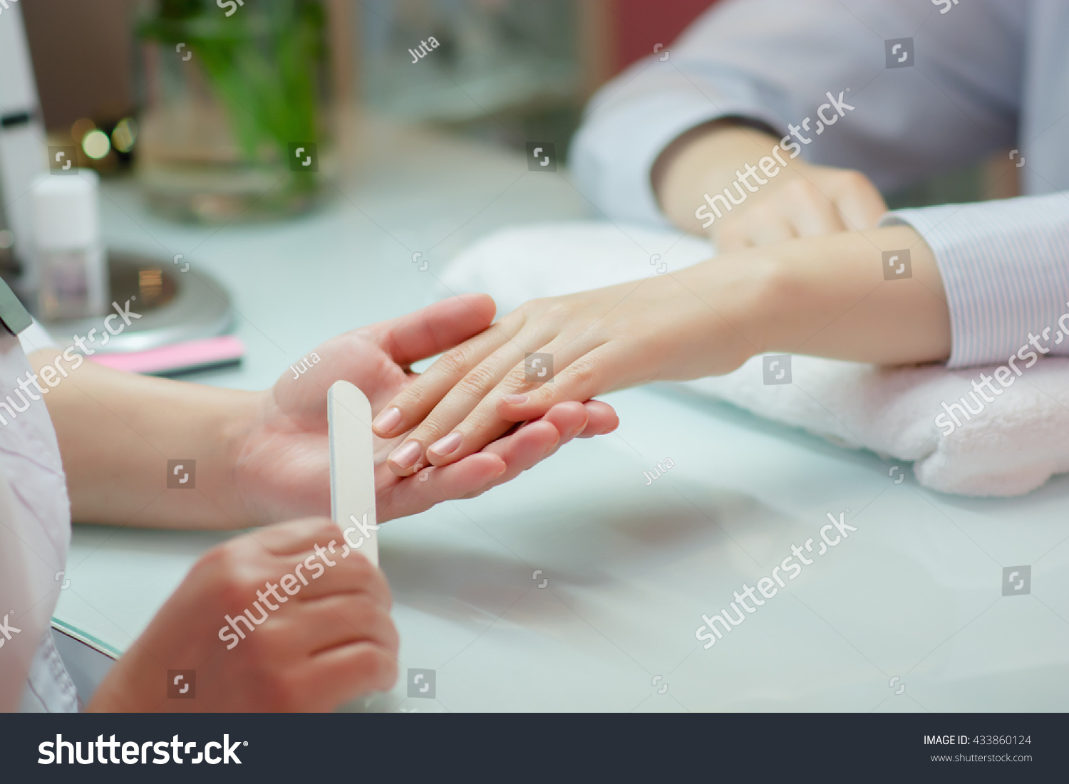 Woman hands receiving a manicure in beauty salon.  Nail filing. Close up, selective focus. #433860124