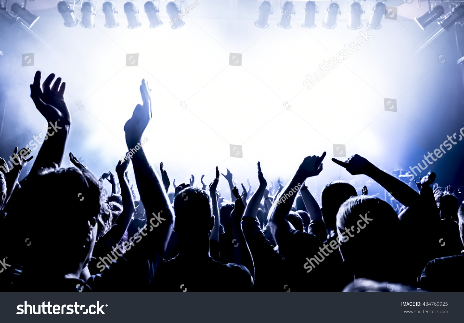 silhouettes of concert crowd in front of bright stage lights #434769925