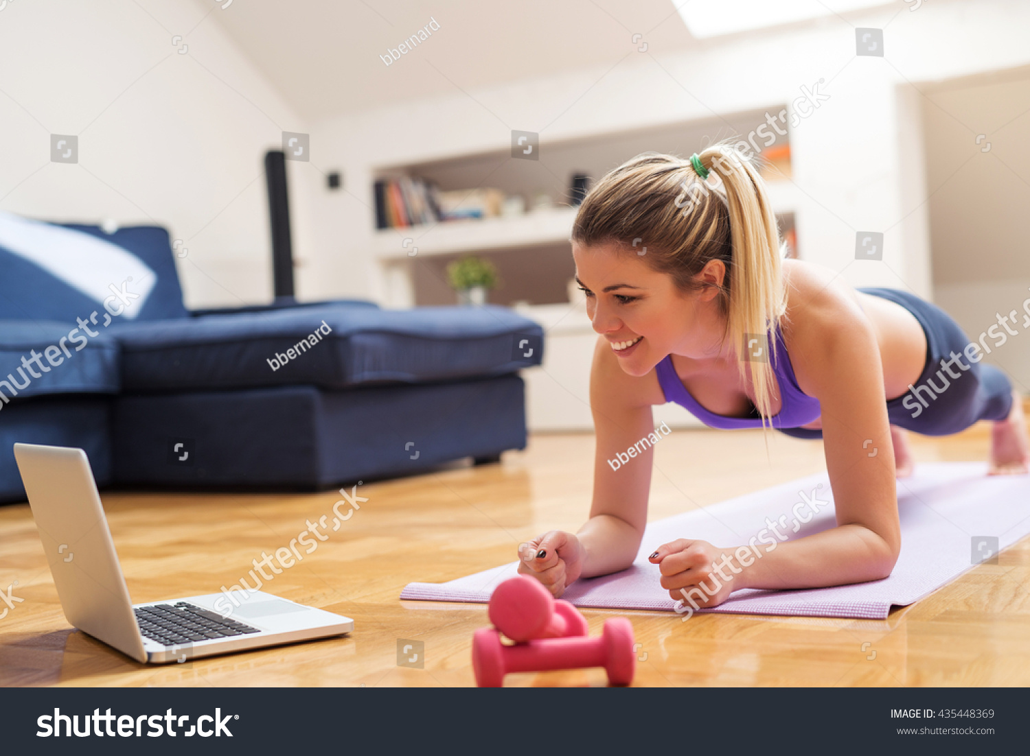 Young girl looking at laptop and doing exercises at home. #435448369