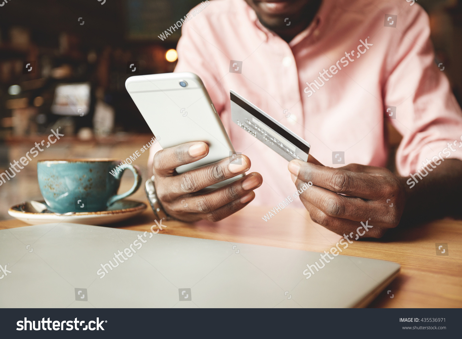 African American man in casual shirt paying with credit card online while making orders via the Internet. Successful black businessman making transaction using mobile bank application. Selective focus #435536971