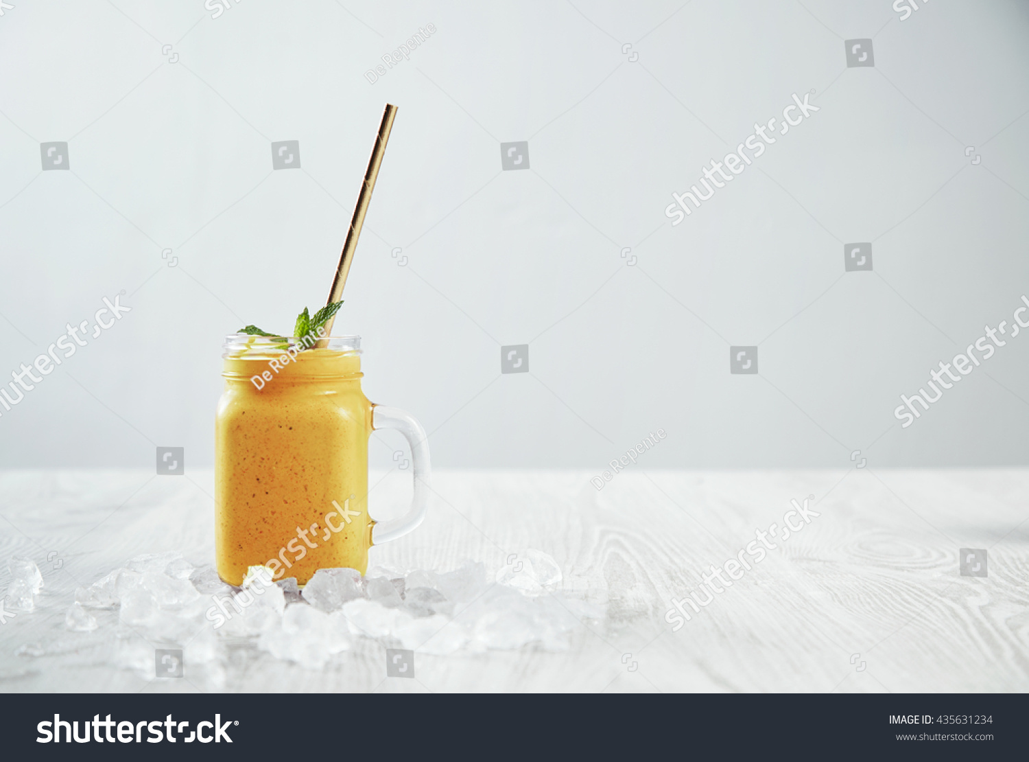 Man hand takes transparent rustic jar with tasty healthly freshly made yellow smoothie from mango, pineapple, banana and passion fruit. Melted ice around isolated on white table Easy to repaint #435631234