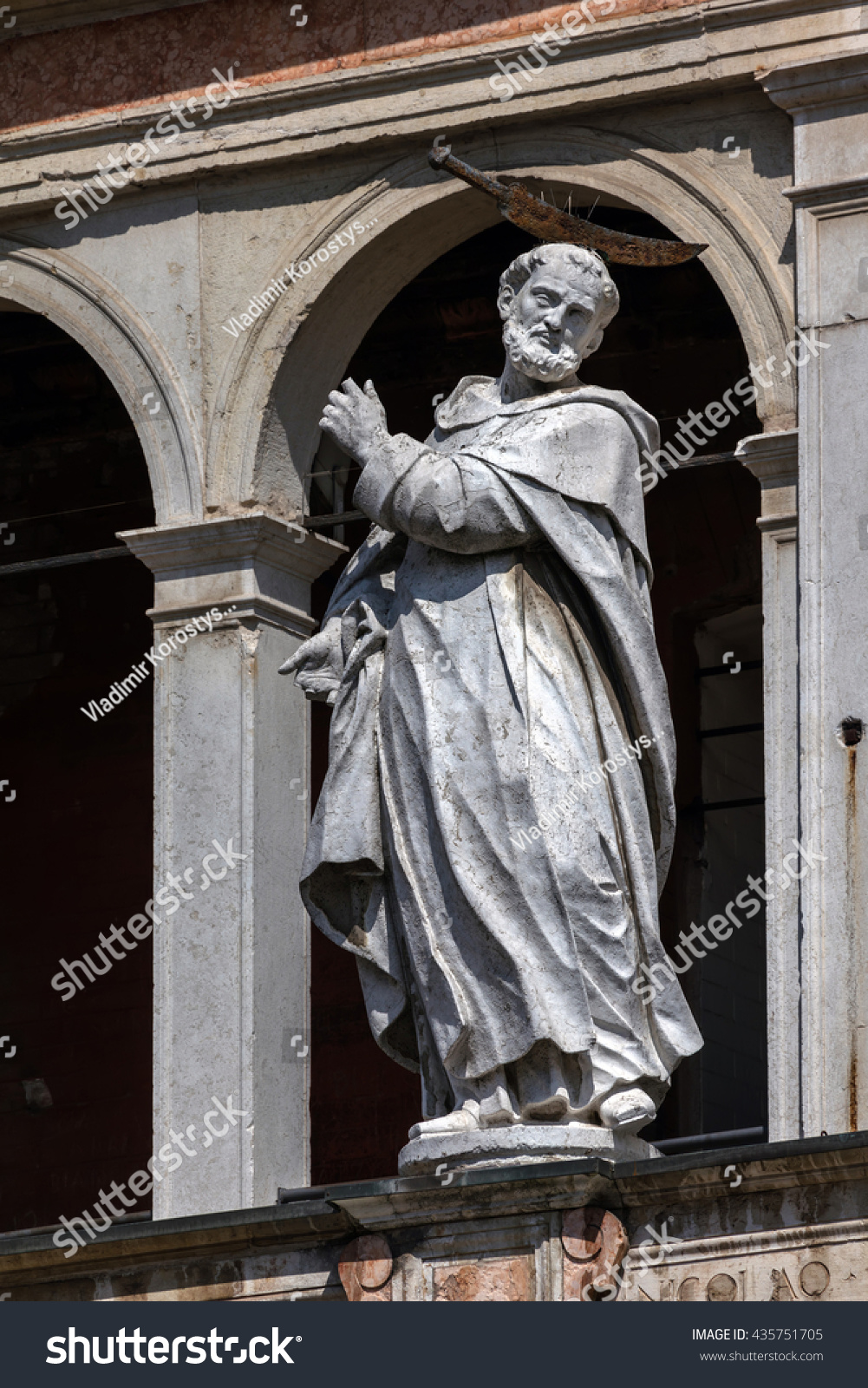Medieval statue of Saint Peter the Martyr with a hatchet in his head decorating the facade of the Cremona Cathedral. #435751705