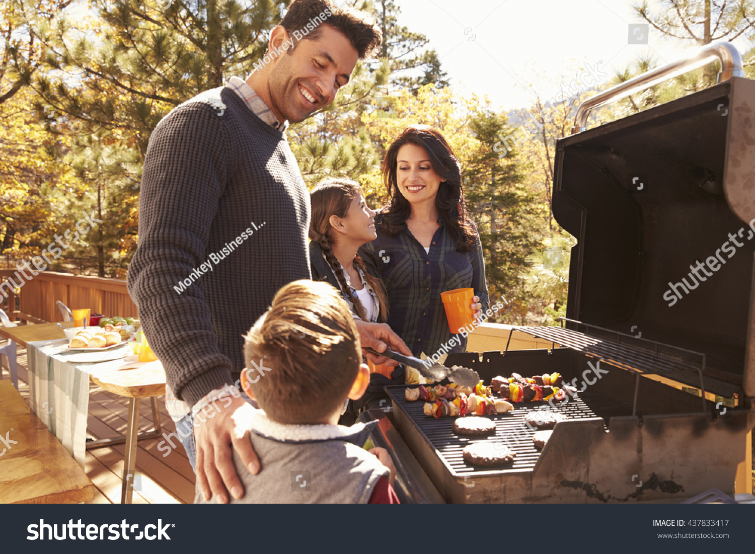 Family barbecuing on a deck in the forest #437833417