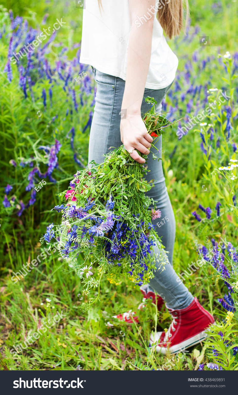 girl holding a bouquet of wildflowers - arms and legs close-up #438469891