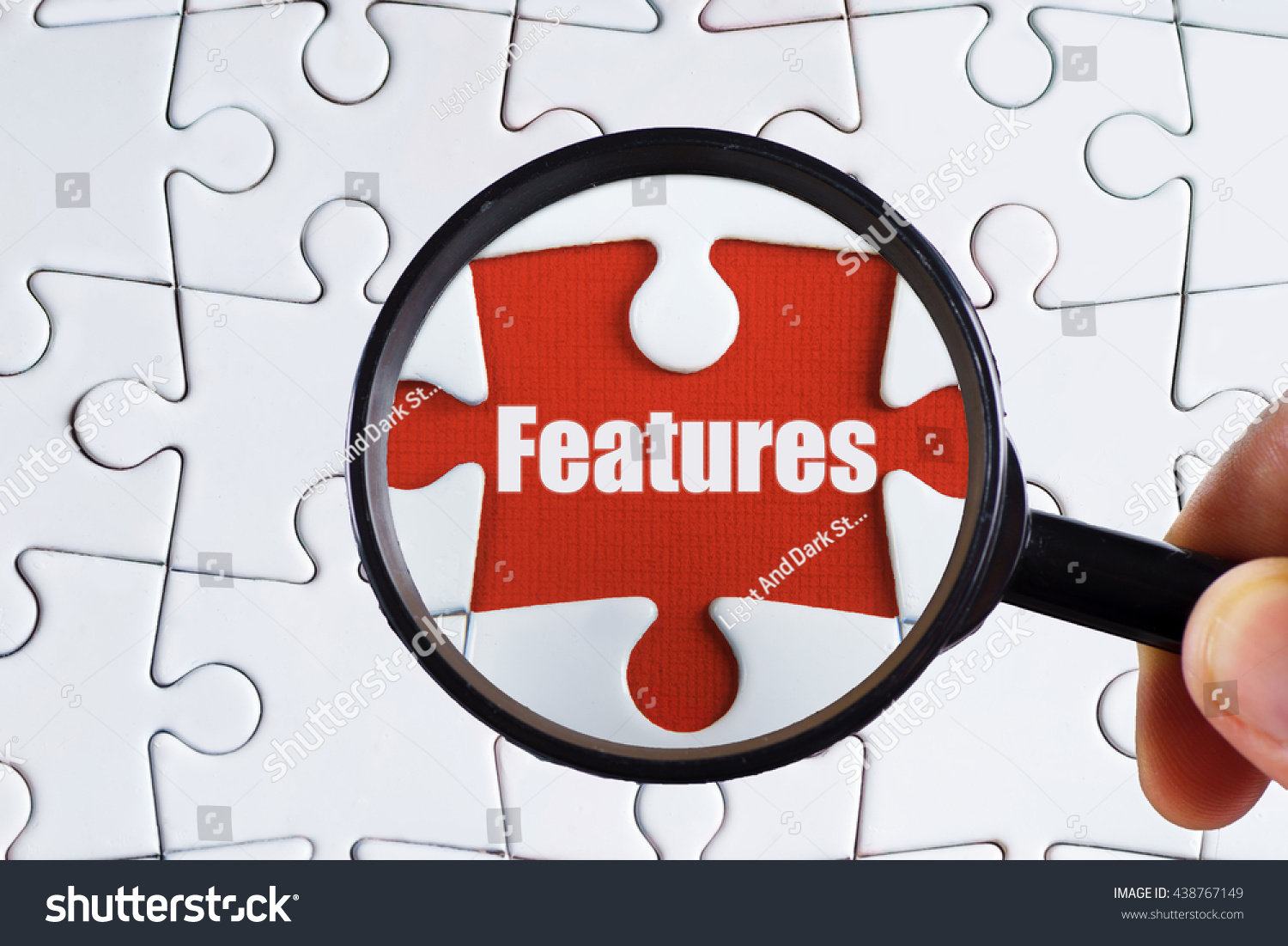 "Features" text on red missing jigsaw puzzle with man right hand hold black magnifying glass searching for missing puzzle peace - business and finance concept #438767149