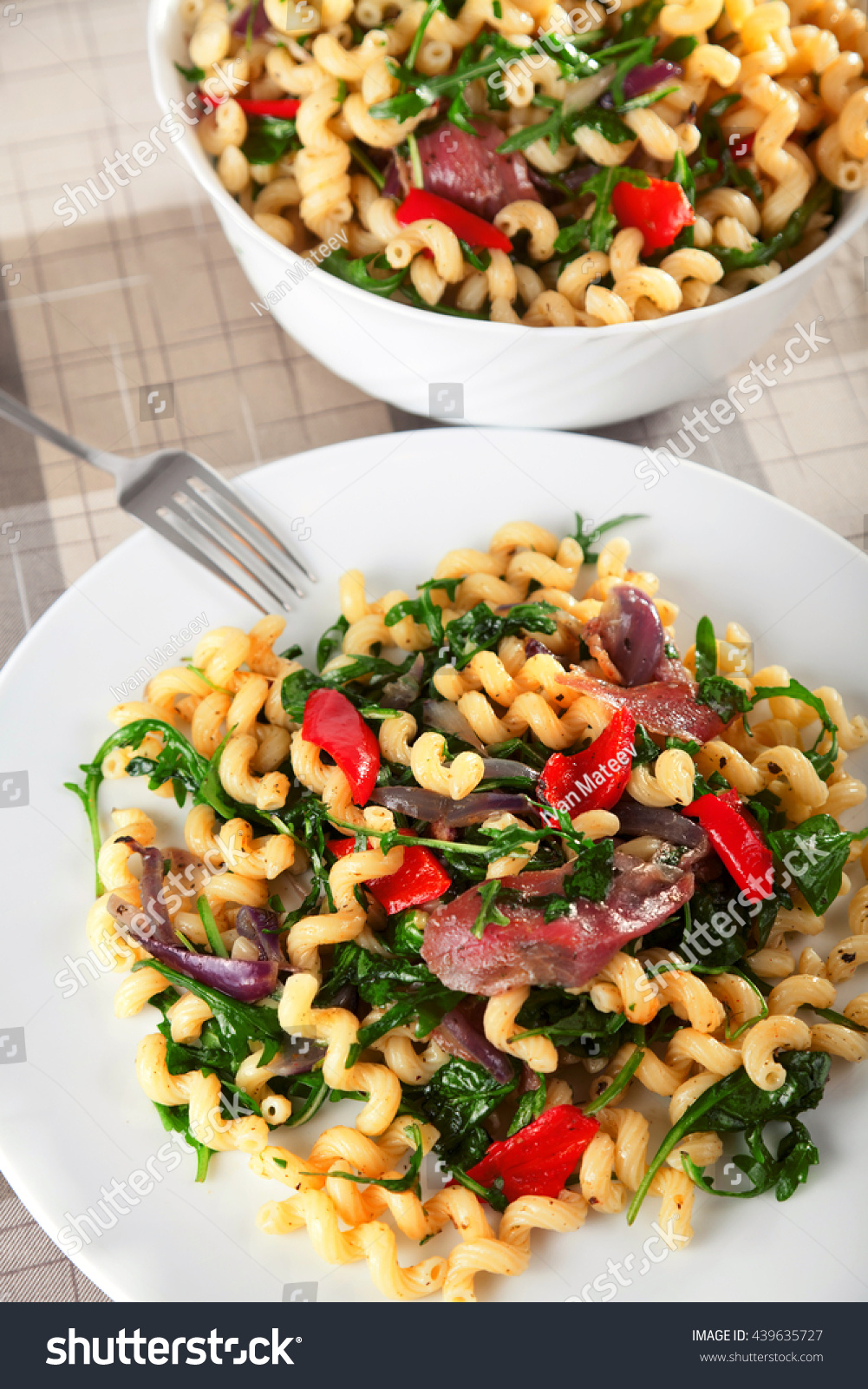 Pasta with prosciutto, rucola and peppers in a big dish ready to be served #439635727
