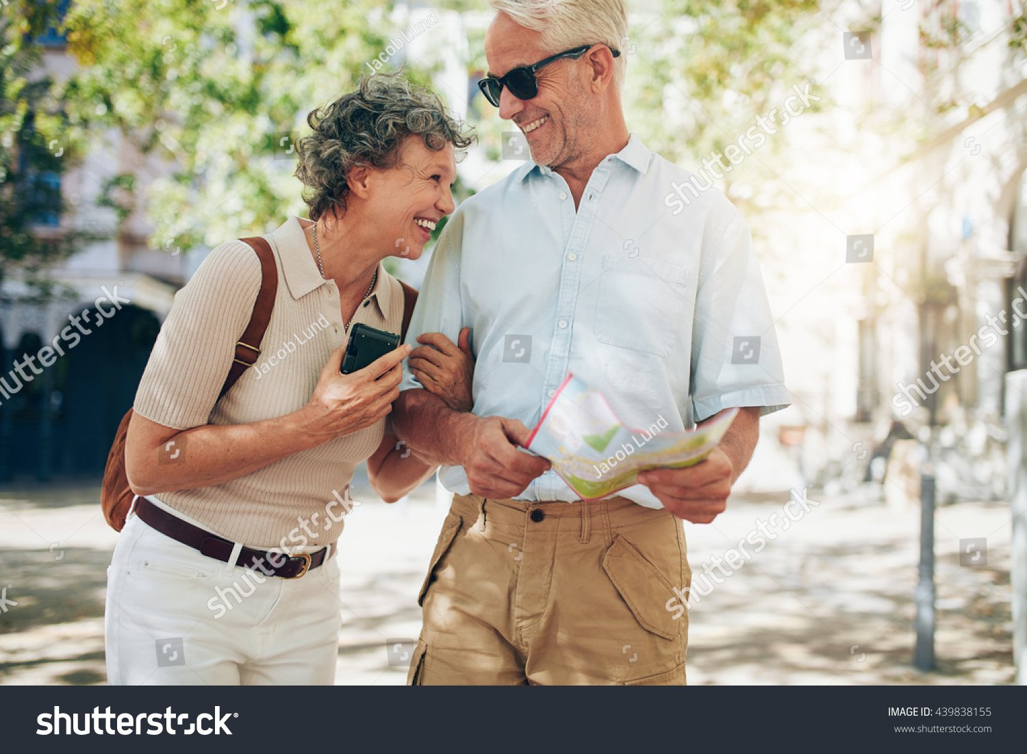 Retired couple walking around the town with a map. Smiling mature man and woman roaming around the city. #439838155