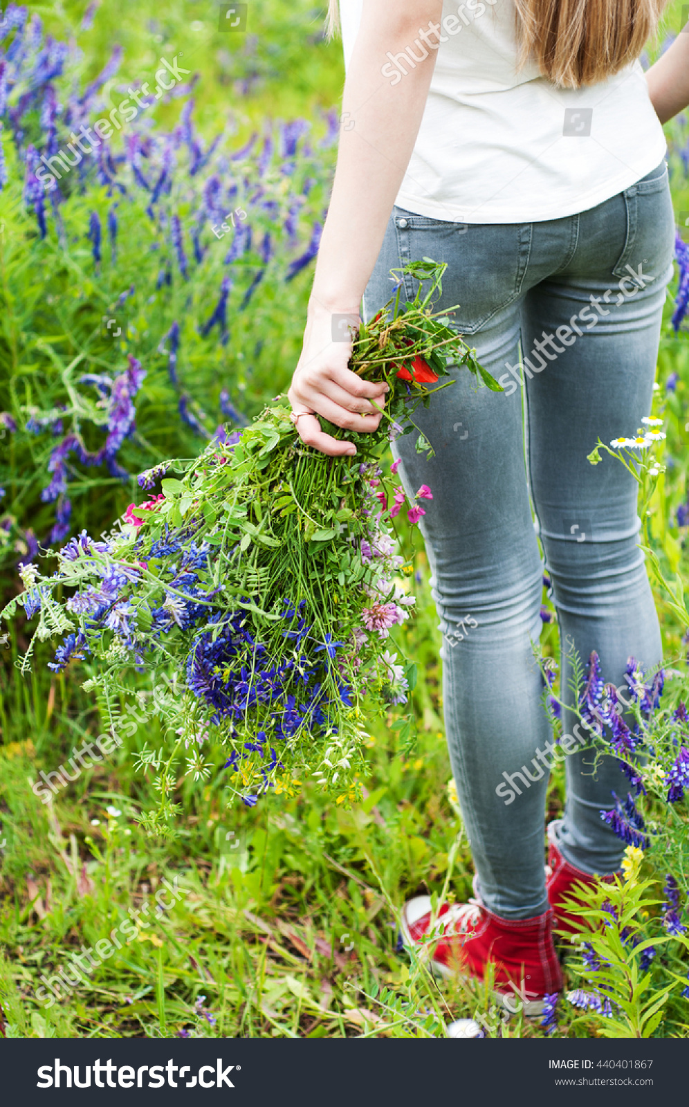 girl holding a bouquet of wildflowers - arms and legs close-up #440401867