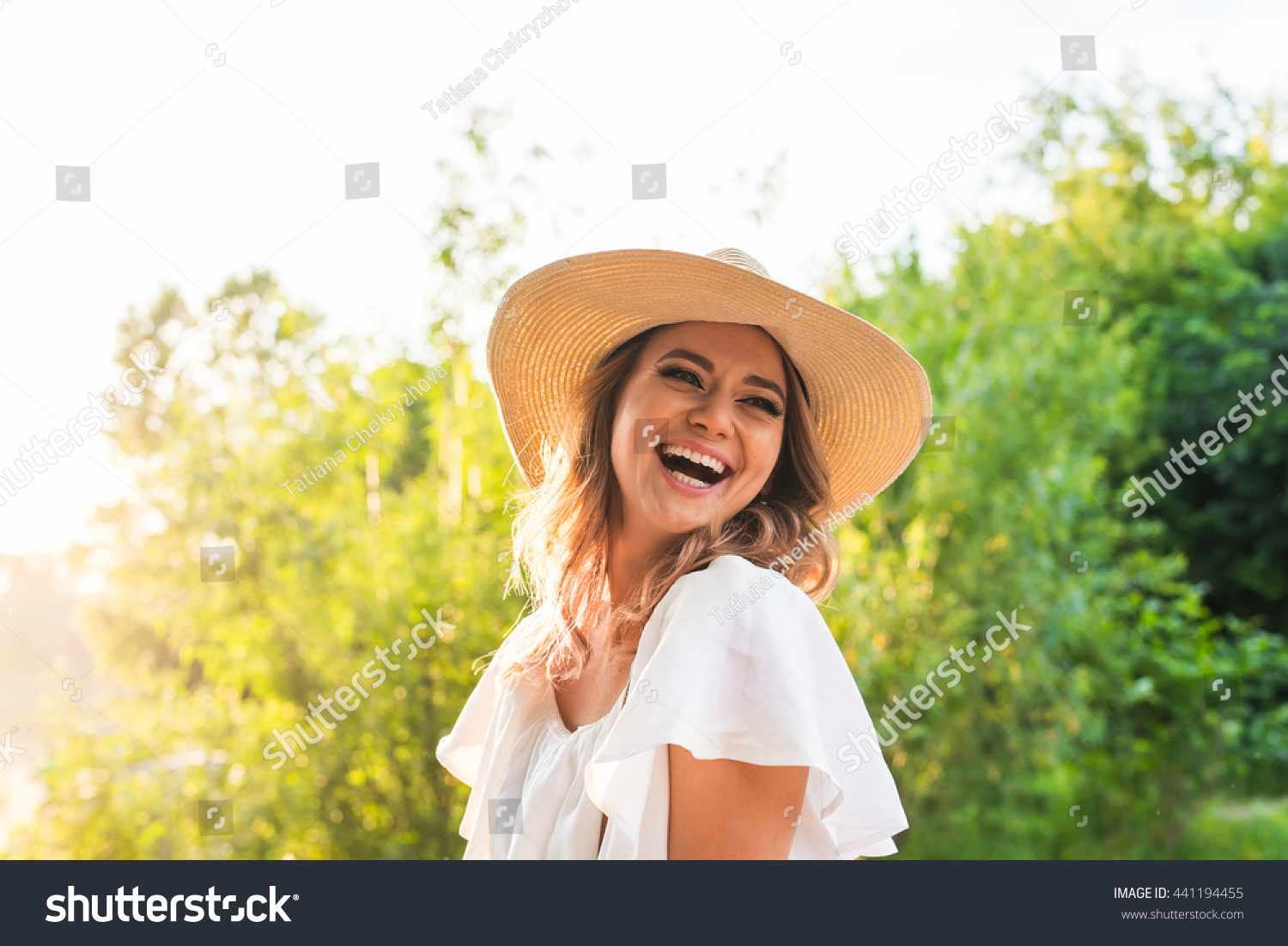 Laughing young woman enjoying her time outside in park with sunset in background. #441194455