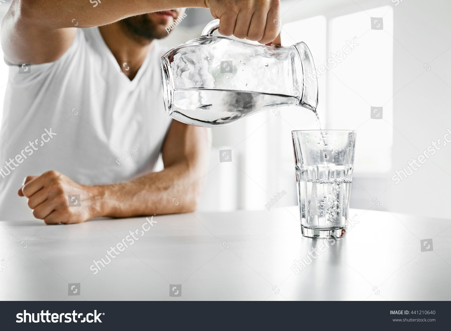 Drink Water. Close Up Of Handsome Young Man Pouring Fresh Pure Water From Pitcher Into A Glass In Morning In Kitchen. Beautiful Athletic Male Model Feeling Thirsty. Healthy Nutrition And Hydration #441210640