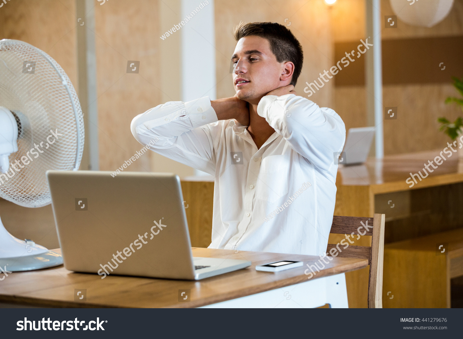 Man enjoying a breeze while using laptop in office #441279676