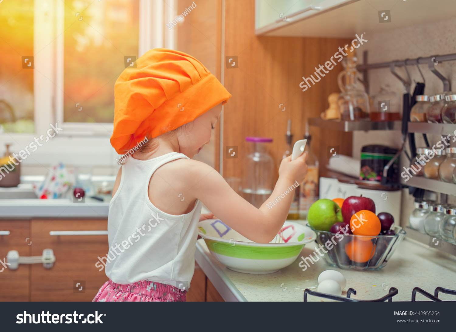 beautiful cute little girl with bonnet making pasta dough in kitchen #442955254