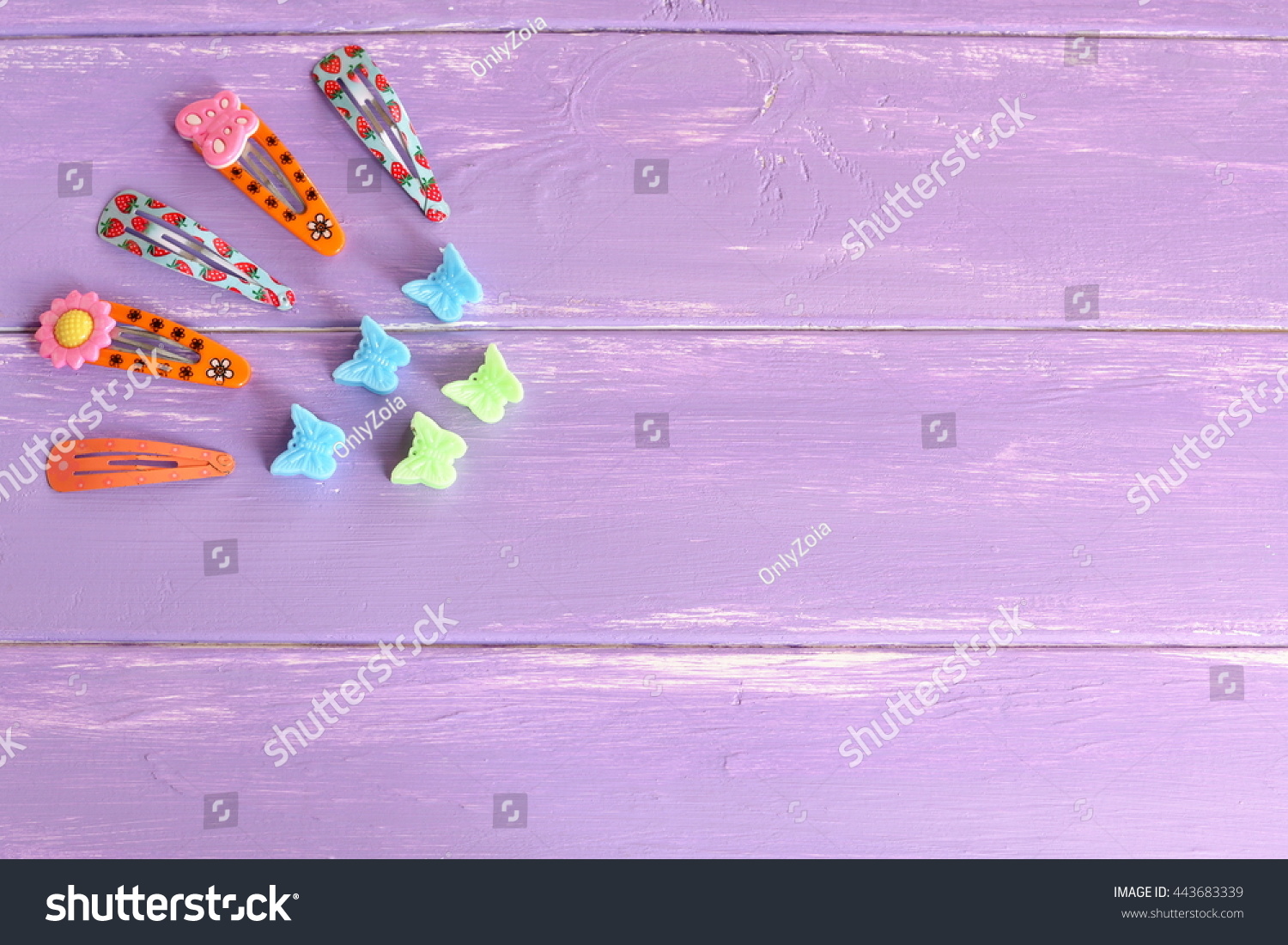 Bright colored hair clips for girls on lilac wooden background with copy space for text. Set of colorful hair clips. Girl fashion background  #443683339