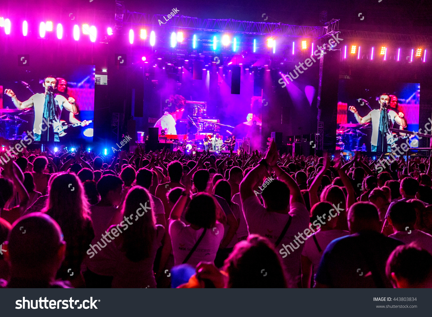 Odessa, Ukraine - June 25, 2016: Large crowd of spectators having fun at stadium, at concert of Ukrainian group Ocean Elzy during creative light and music show. Cheerful bright show in party club #443803834