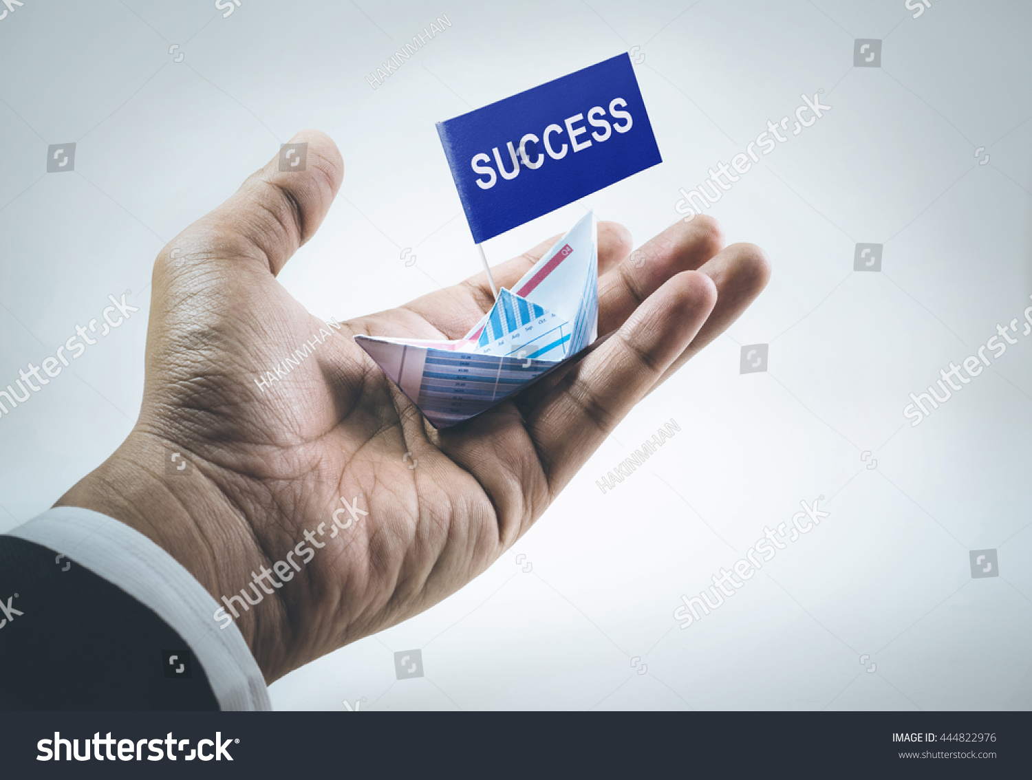 Success word on flag with boat made of paper graph in businessman hand.For business financial concept. #444822976