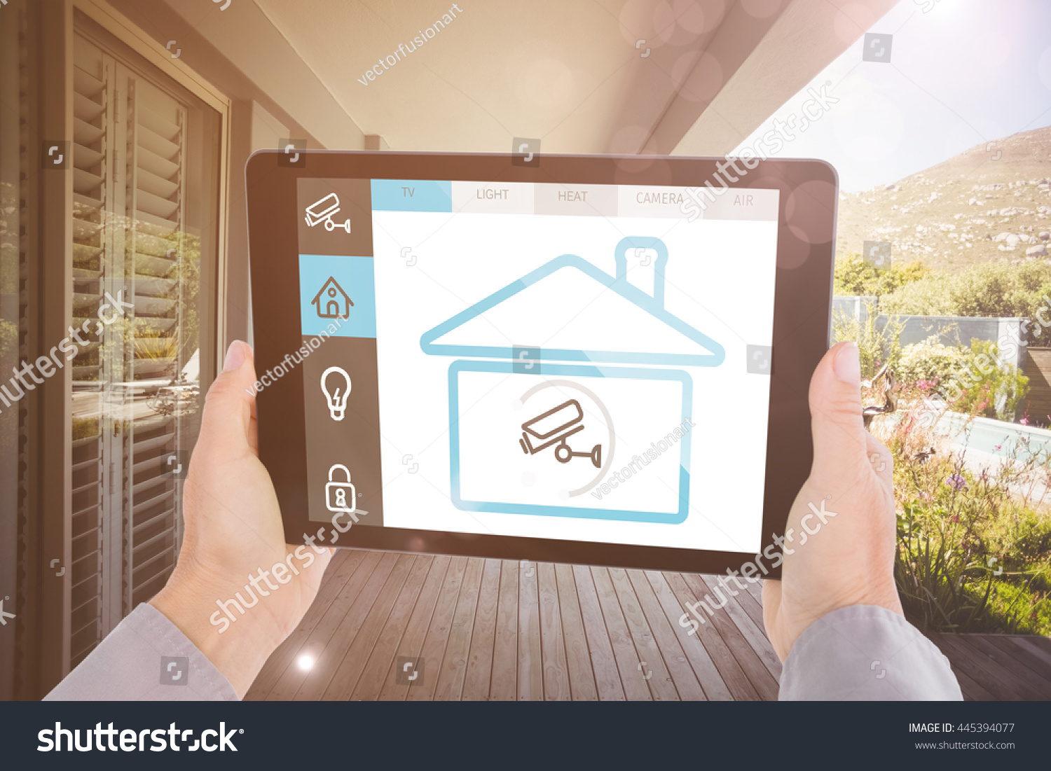 Cropped hand of man holding digital tablet against stylish outdoor patio area #445394077