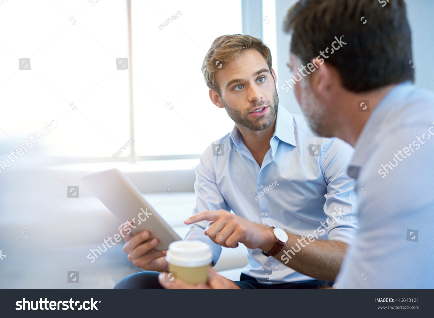 Handsome young business entrepreneur holding a digital tablet while talking about ideas with his mature corporate manager #446643121