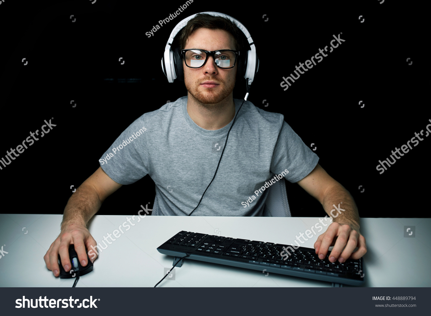 technology, gaming, let's play and people concept - young man or hacker in headset and eyeglasses with pc computer playing game and streaming playthrough or walkthrough video over black background #448889794