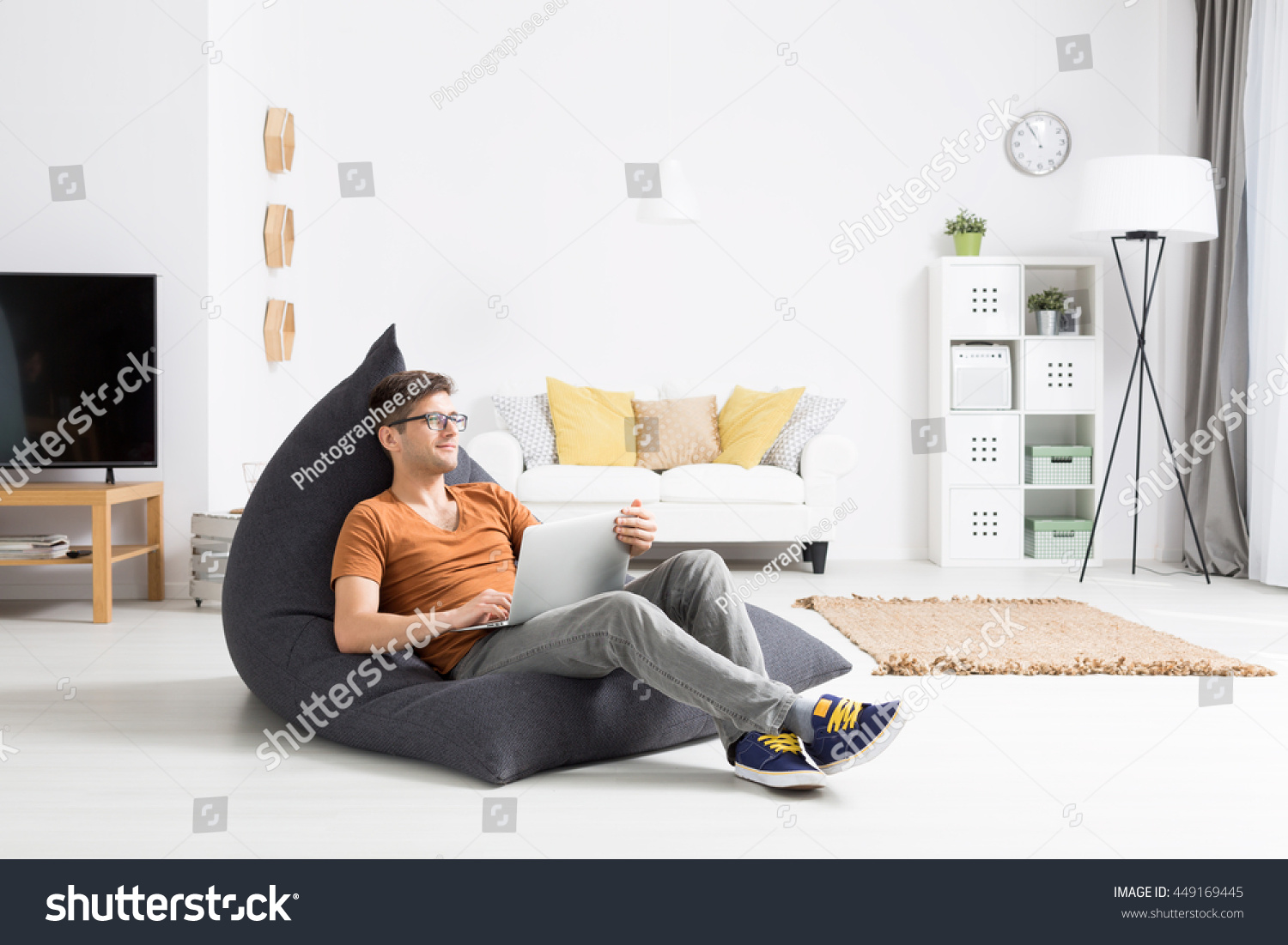 Young man relaxing comfortably in a grey sitting sack in a bright studio flat #449169445