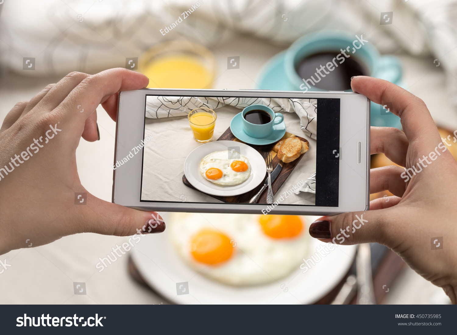Woman using smartphone to take photos of her breakfast #450735985