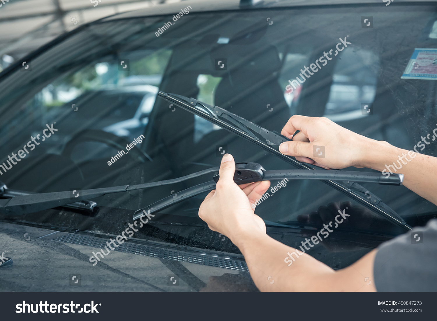 Man is changing windscreen wipers on a car #450847273