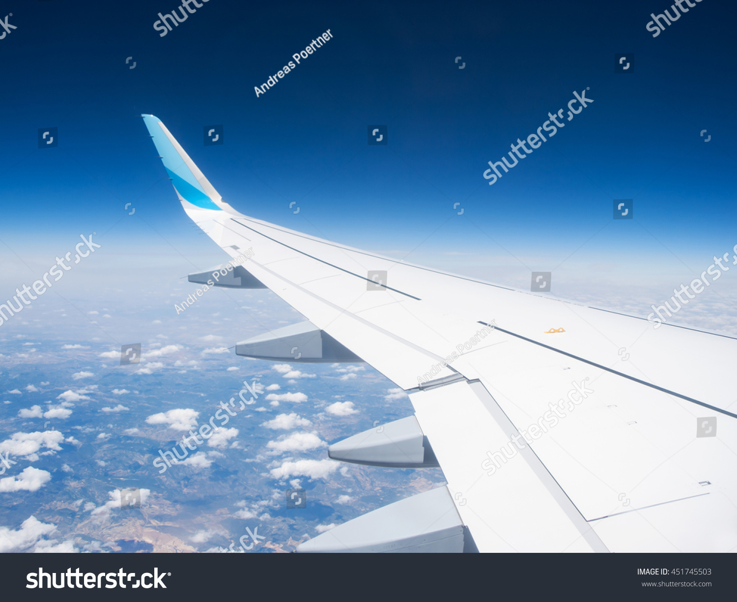 Wing of a airplane with winglet over the clouds #451745503