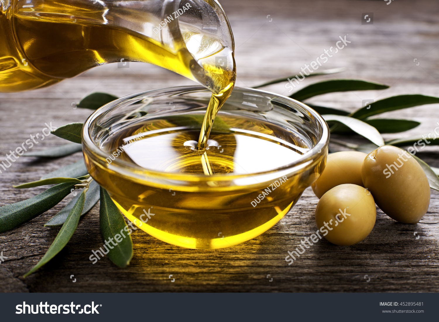 Bottle pouring virgin olive oil in a bowl close up #452895481