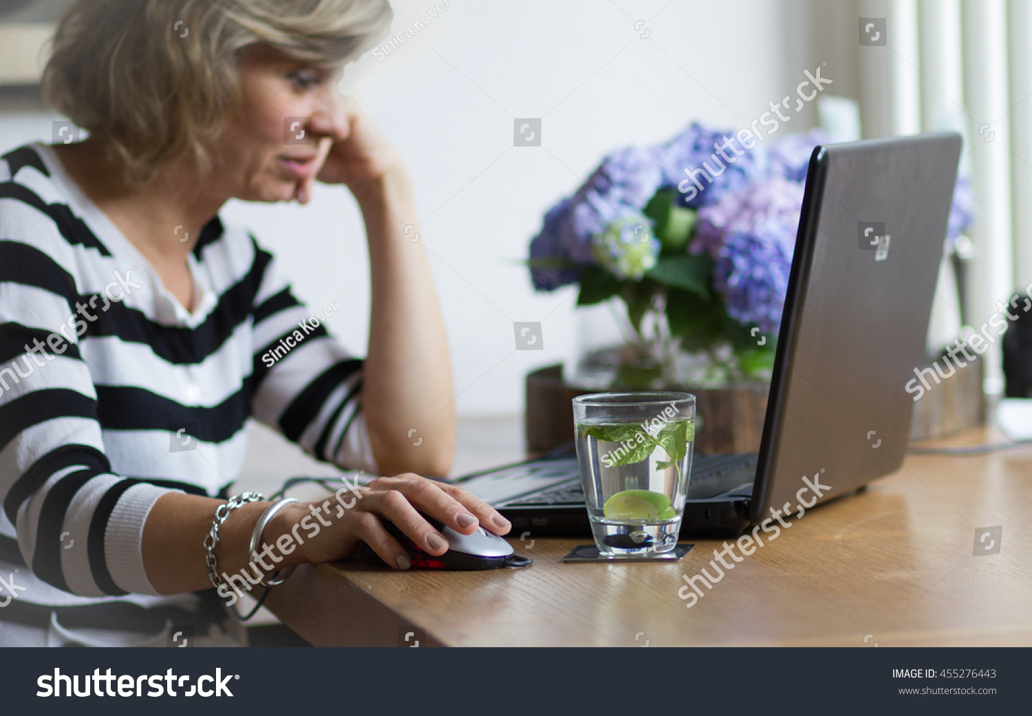 Attractive middle-aged blonde businesswoman working, using portable computer, looking at the monitor #455276443
