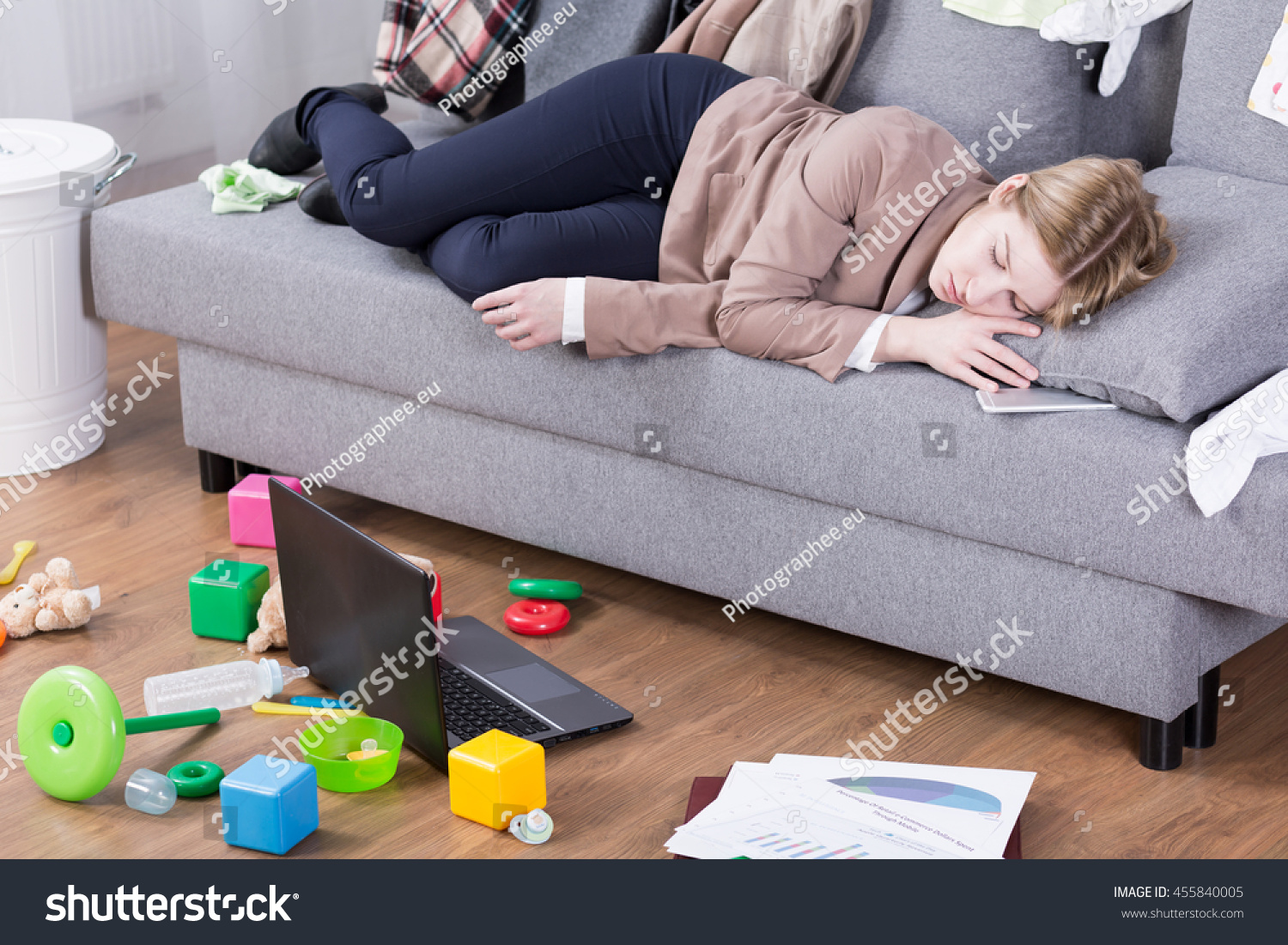 Young mother sleeping in her office clothes on a sofa in a messy living room #455840005