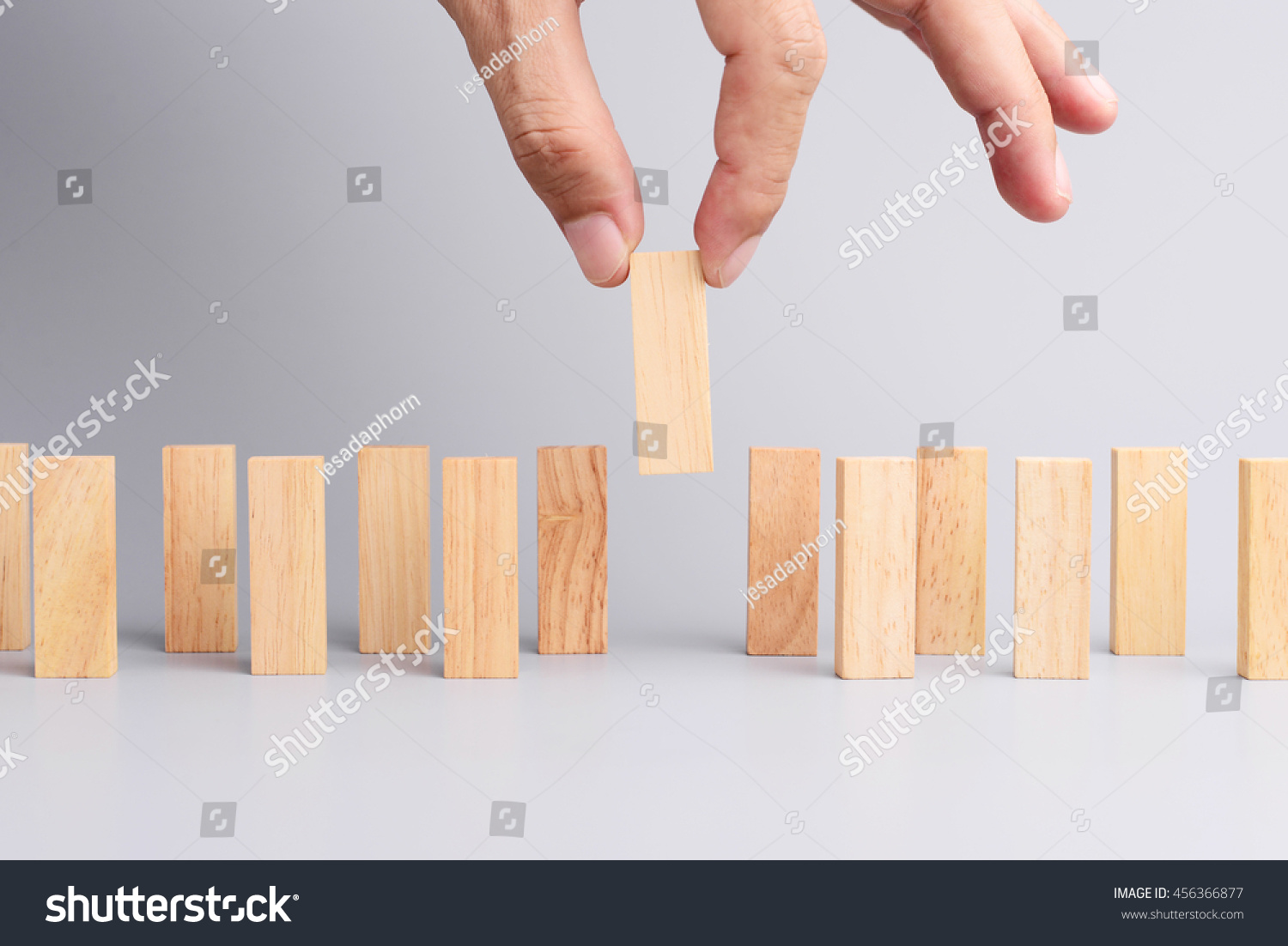 Man hand pick one of wood block from many wood block in row, metaphor to business concept in choose ideal person from many candidate. Gray background, side view. #456366877