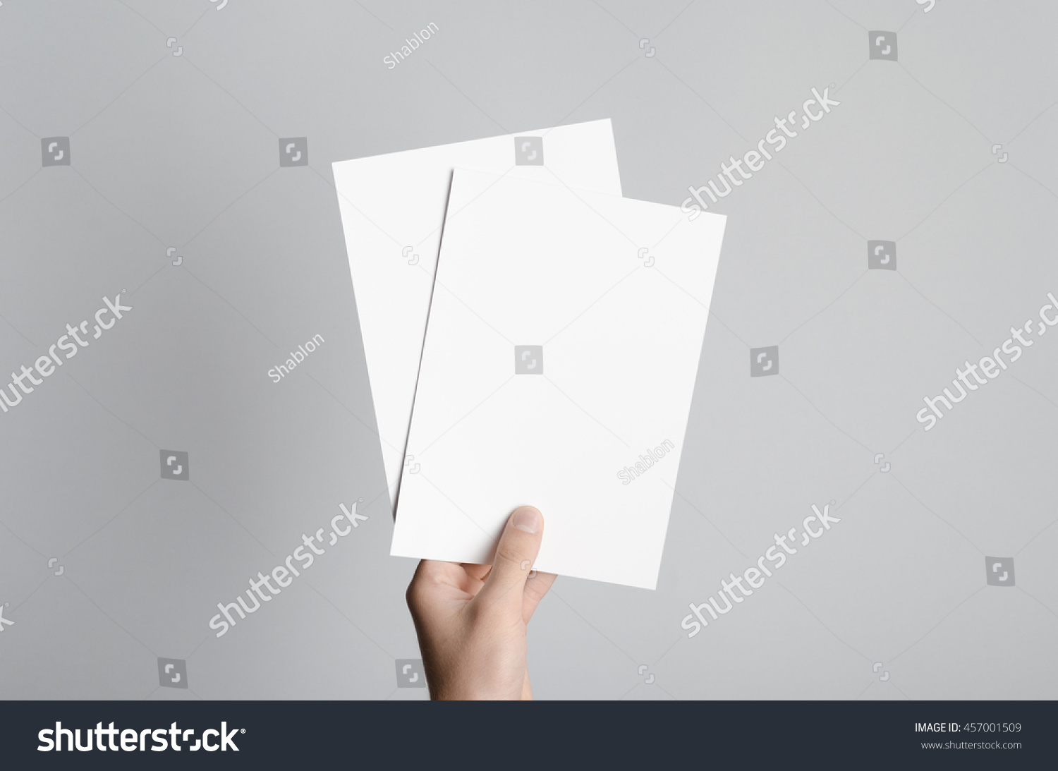 A5 Flyer / Invitation Mock-Up - Male hands holding blank flyers on a gray background. #457001509