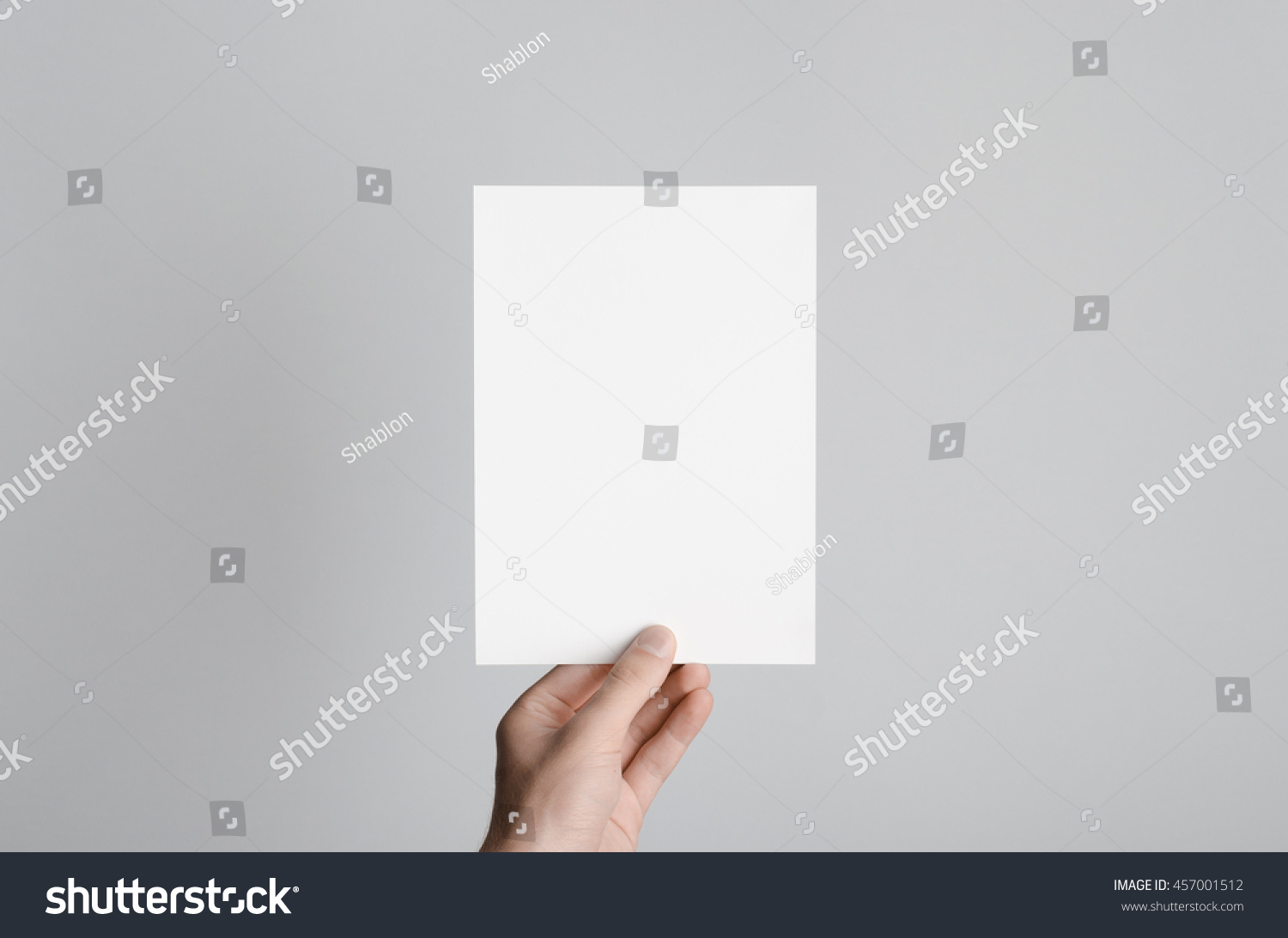 A5 Flyer / Invitation Mock-Up - Male hands holding a blank flyer on a gray background. #457001512