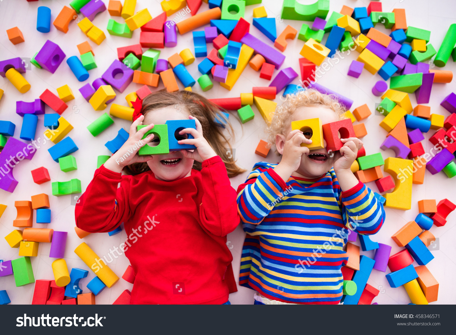 Happy preschool age children play with colorful plastic toy blocks. Creative kindergarten kids build a block tower. Educational toys for toddler or baby. Top view from above. #458346571