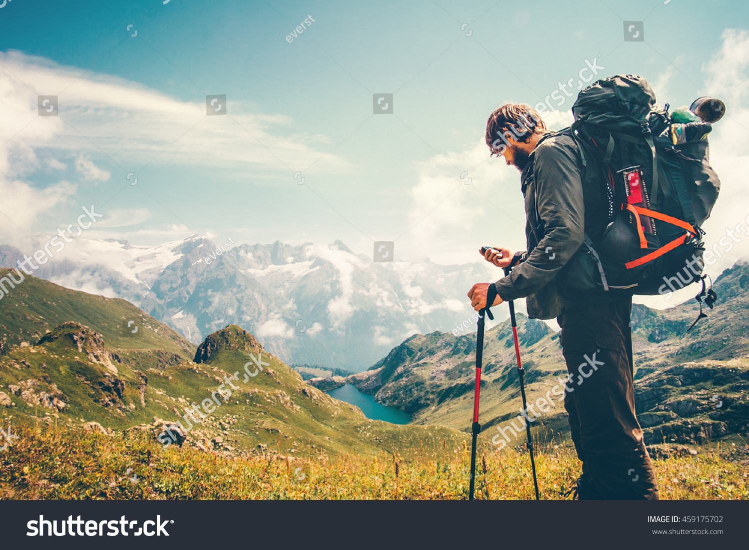 Man Traveler backpacker with gps navigator tracker looking for coordinates Travel Lifestyle concept mountains and lake on background survival adventure vacations outdoor #459175702