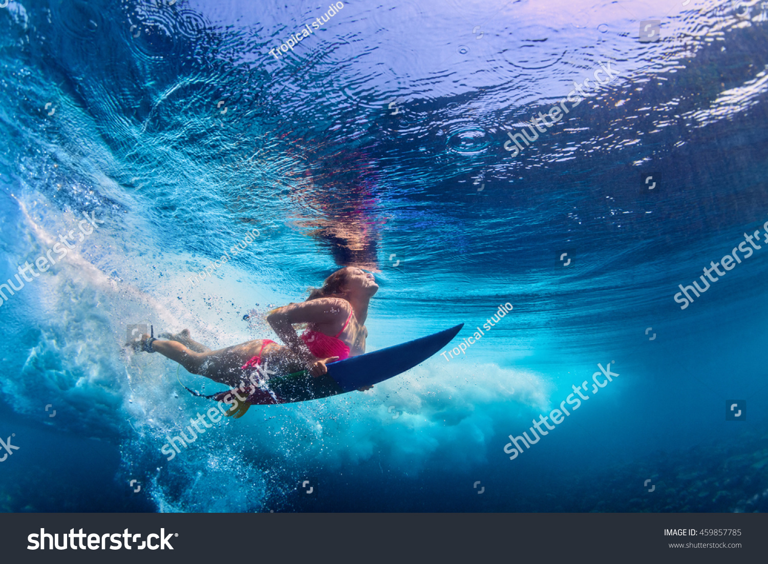 Young girl wearing bikini in action - surfer with surf board dive underwater under ocean wave. Family lifestyle, people water sport adventure camp and beach extreme swim on summer vacation with child. #459857785