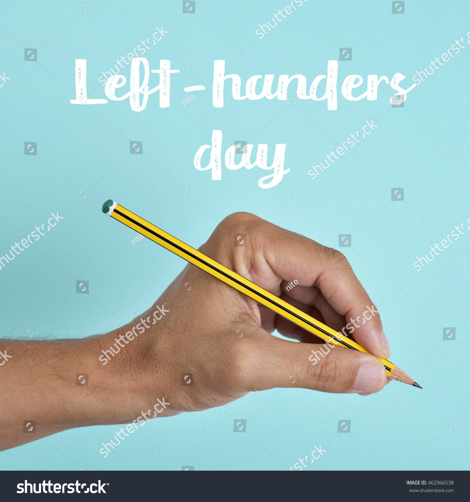 the text left-handers day and the hand of a left-handed man with a pencil, against a blue background #462966538